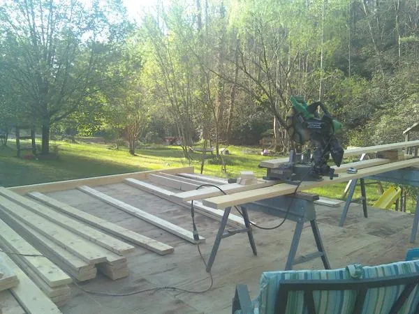 Miter saw and framing lumber on a deck under construction in Benton